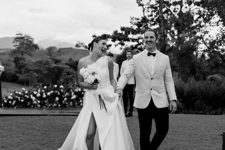 A newlywed couple holding hands and smiling as they walk down the aisle during their wedding ceremony.