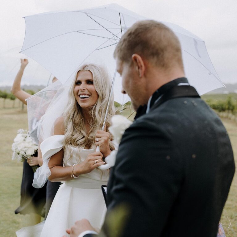 The bride holding an umbrella.