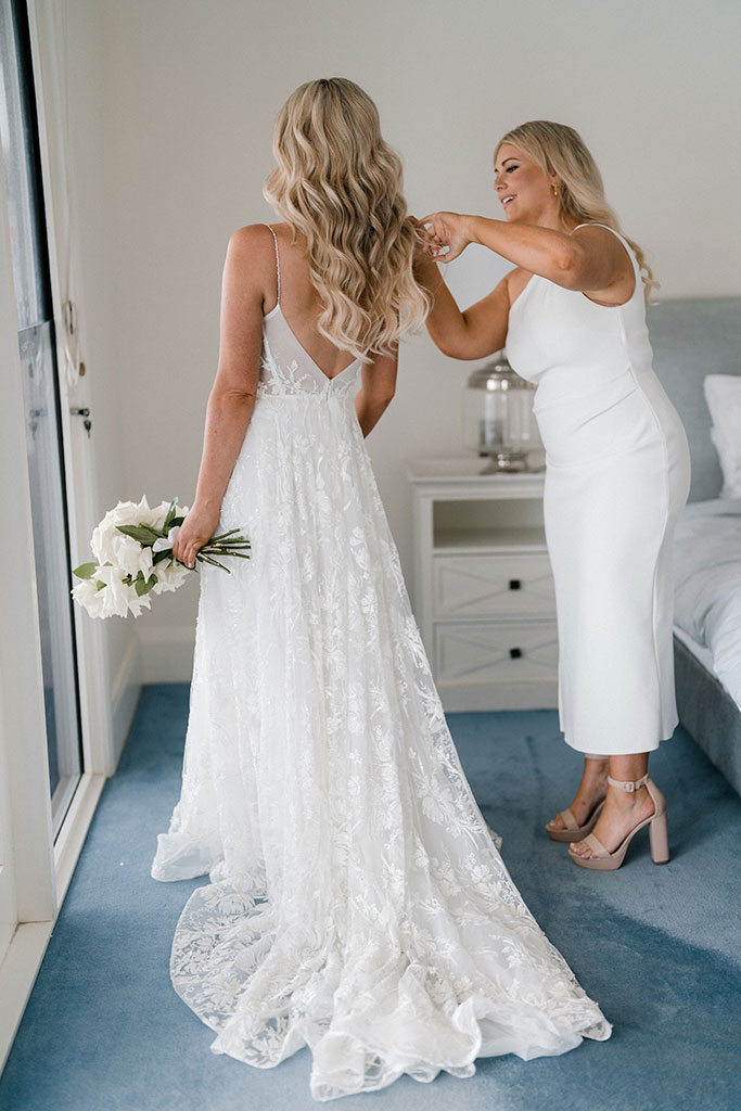 A woman fixing the brides dress.