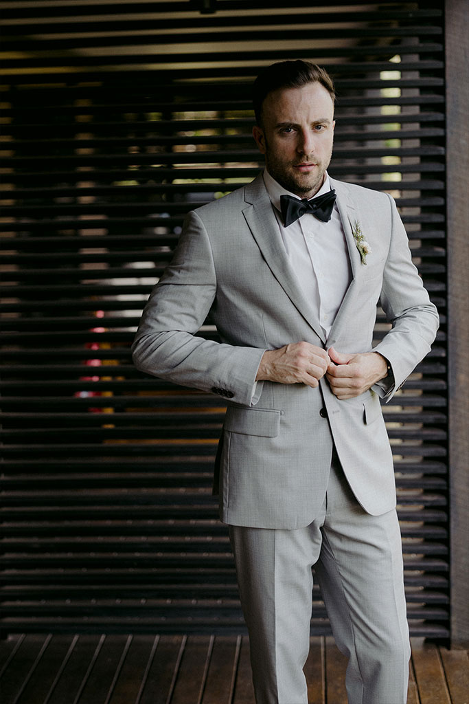 A man buttoning his tuxedo.
