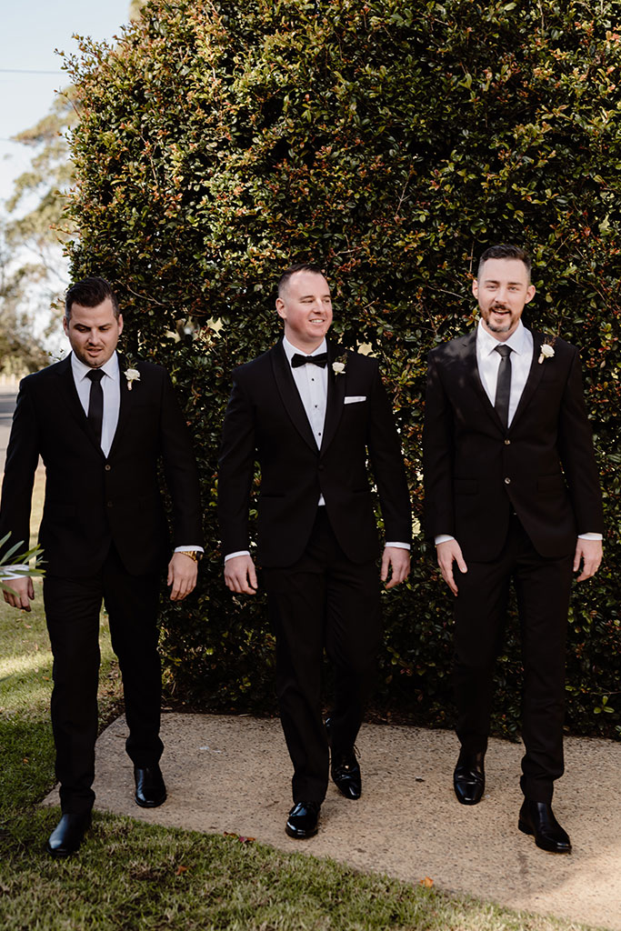Three men walking wearing tuxedos.