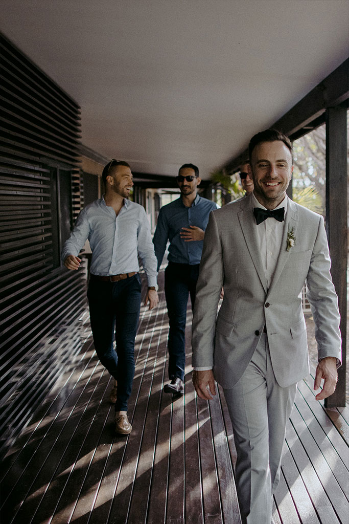 A groom and two men in tuxedos walking together.