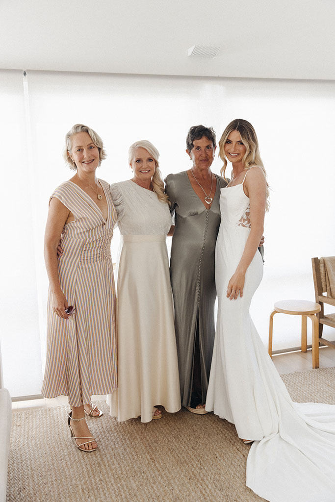 A bride posing with three women wearing gowns.