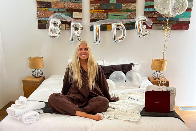 The bride posing in front of the sign that says "bride" out of balloons.