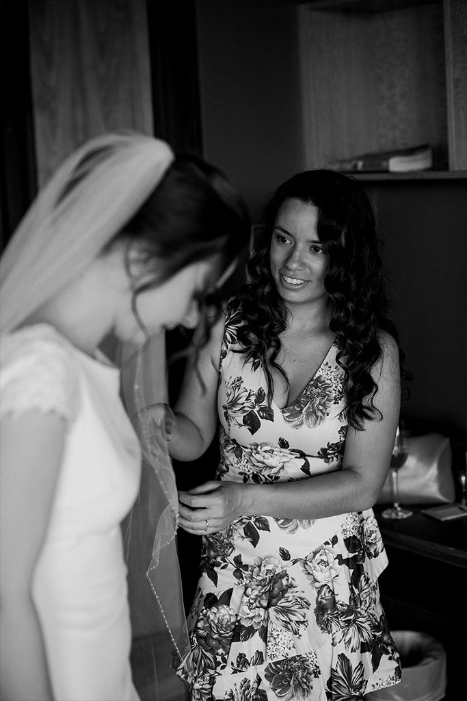 A woman helping the bride with her dress.