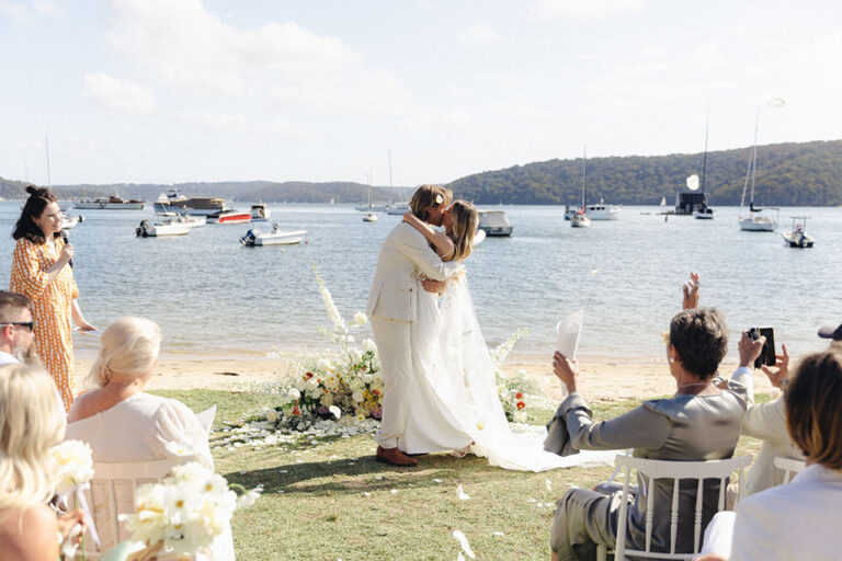 A beach wedding with boats in the background.
