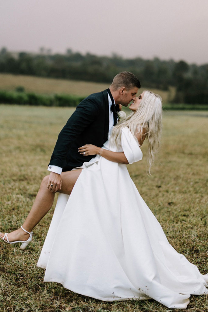A bride and groom share a kiss in a beautiful field on their wedding day.