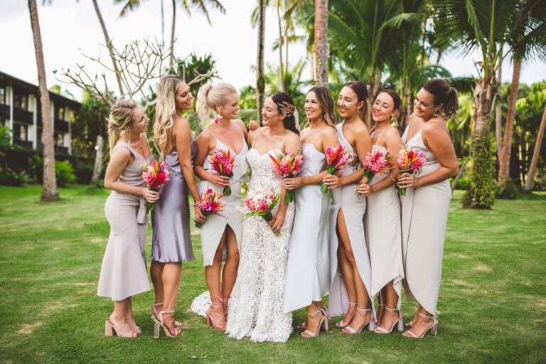 Bridesmaids in white dresses holding pink flowers.