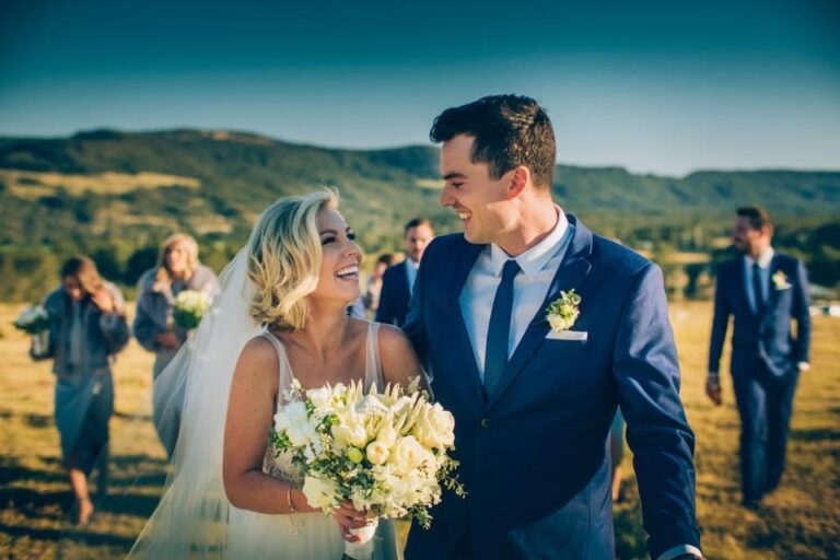 A bride and groom walking through a field on their wedding day.