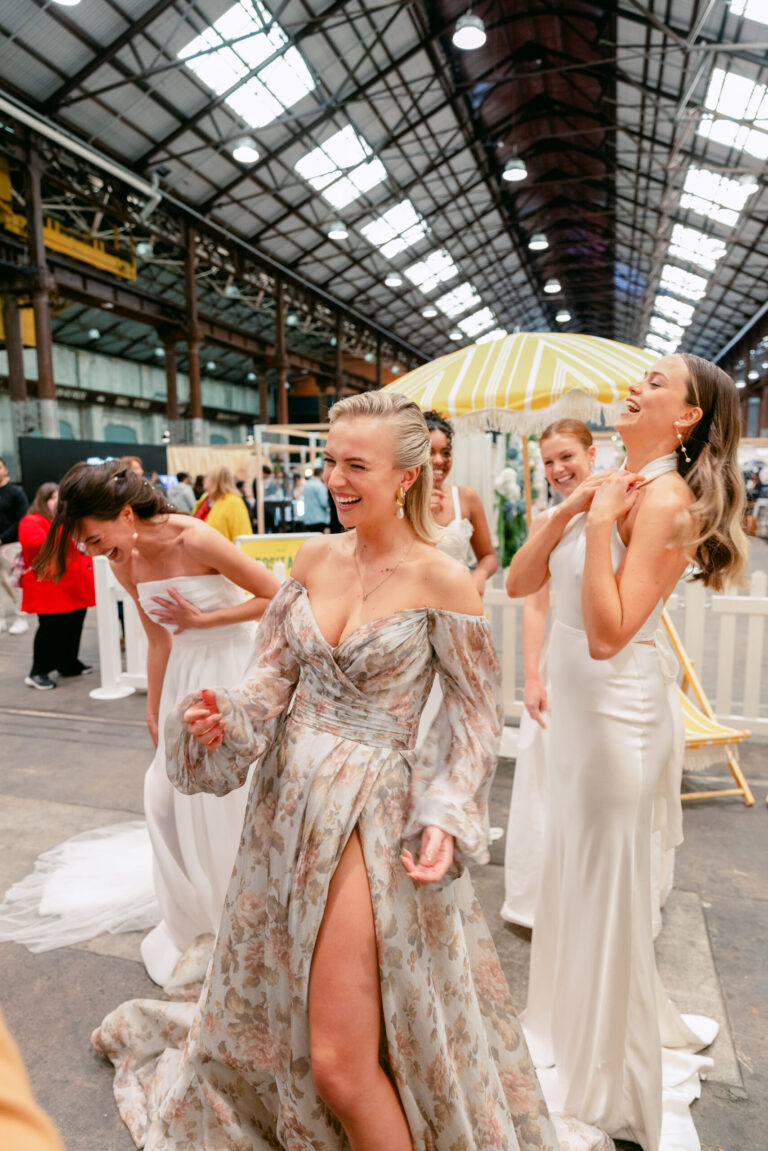 Candid photo of five women wearing beautiful dresses laughing.