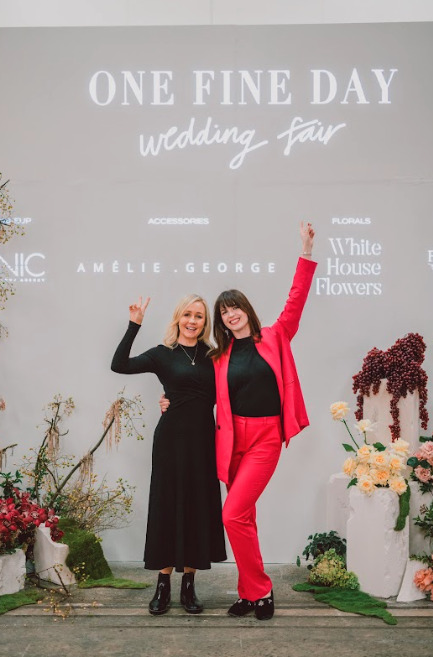 Two women pointing at a sign that says "One Fine Day".