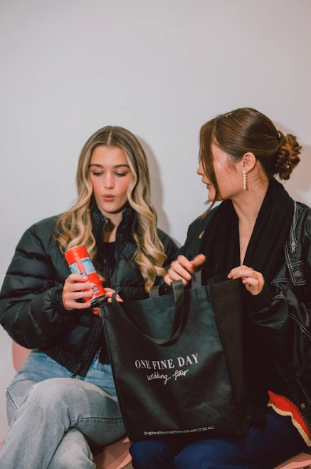 Two women sitting on a couch, holding a shopping bag.
