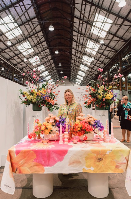A woman in the middle of a wide variety of beautifully arranged flowers.