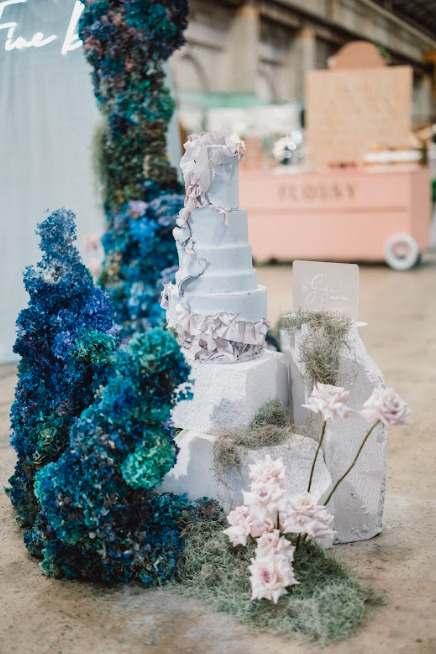 A wedding cake adorned with blue and white flowers.