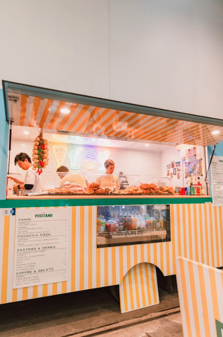 A food truck with people inside it preparing food.