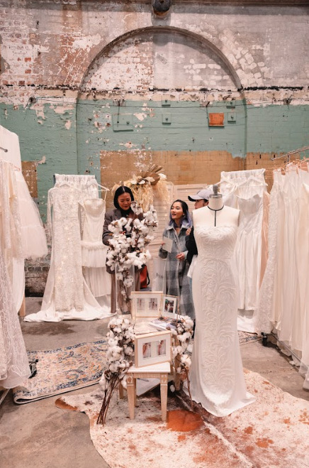A woman admiring wedding dresses in a store.