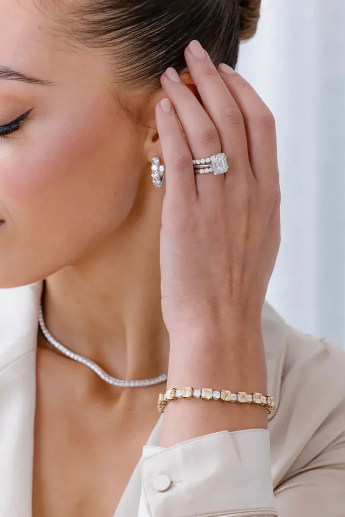 A woman in a white blouse showcases a diamond bracelet, highlighting the elegance of Charles Rose Jewellers' best engagement ring