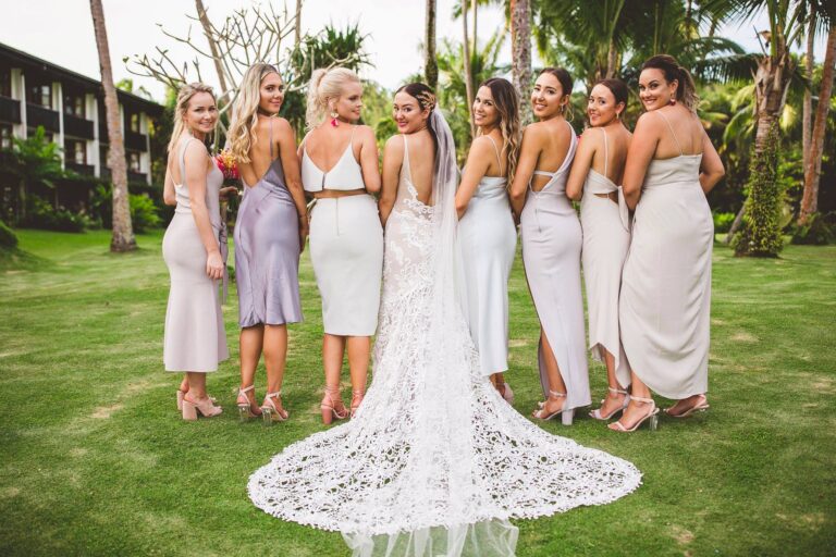 Bridesmaids smiling and posing for a photo in front of palm trees at a tropical location.