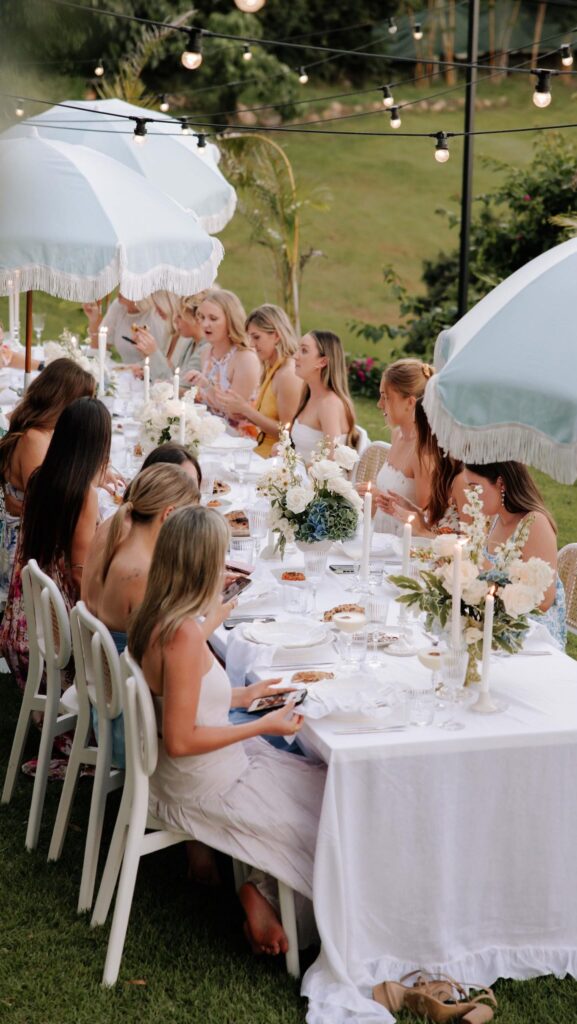 Group of women sitting under white umbrellas, enjoying a stylish outdoor setup by Cloth and Confetti, best wedding event hire Melbourne.