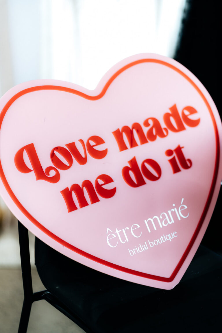 A heart-shaped sign with the words "Love made me do it" written on it.