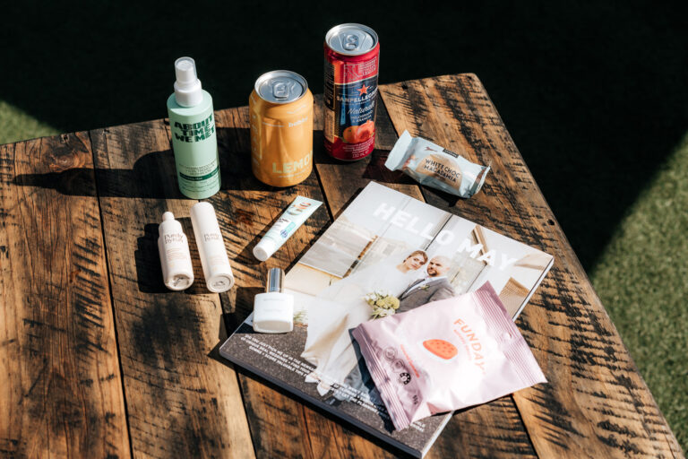 A magazine, water bottle, and soda can on a wooden table.
