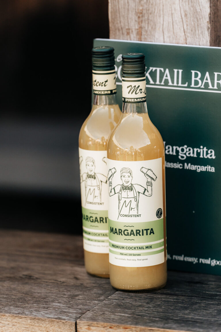 Two bottles of margarita mix on a wooden table.