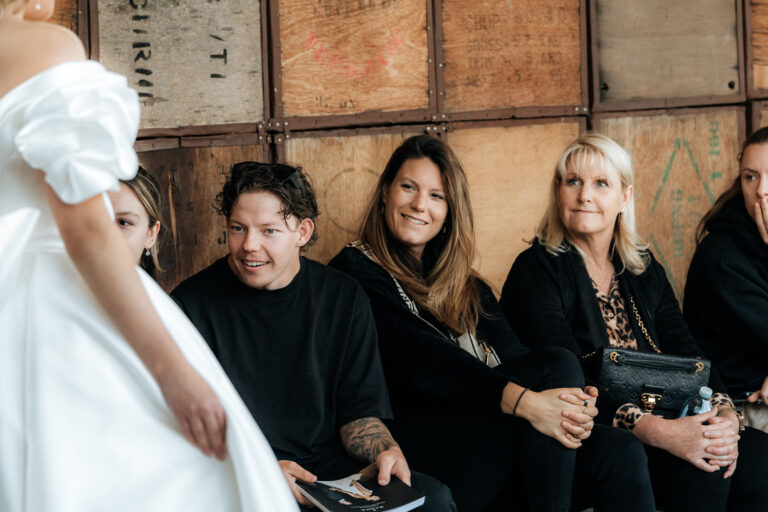 A group of women sitting on a bench, with one woman wearing a wedding dress.