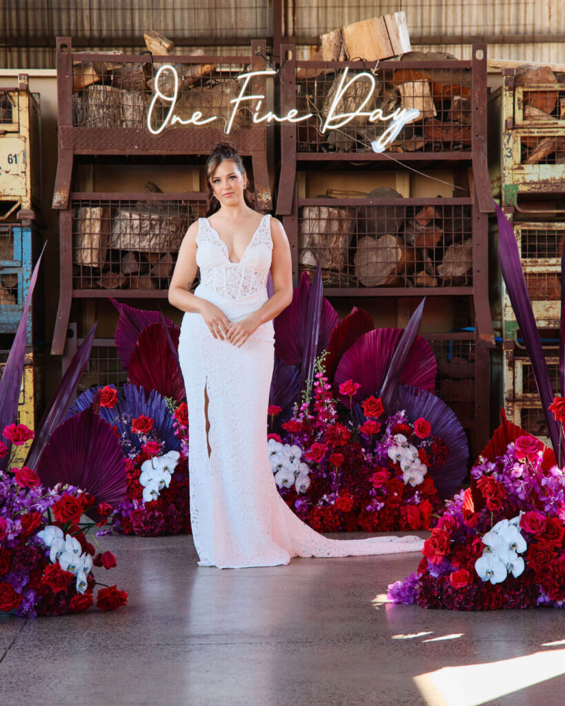Model posing in a deep V-neck sleeveless wedding dress with high-thigh slit at a bridal runway show in Melbourne.