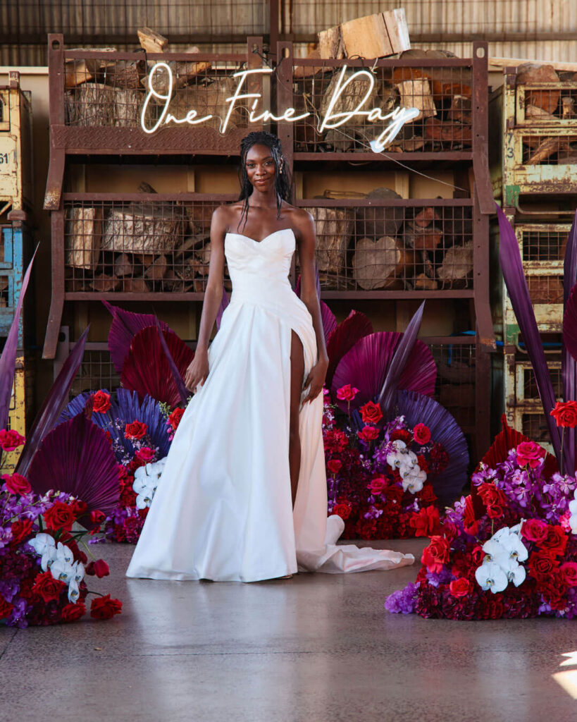 Model posing in a strapless ball gown wedding dress with thigh-high slit at a bridal runway show in Melbourne.