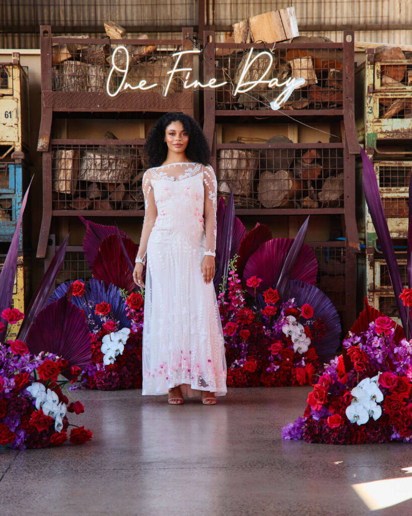 Woman posing in a strappy wedding dress with delicate floral pattern and sheer overlay at a bridal runway show in Melbourne.