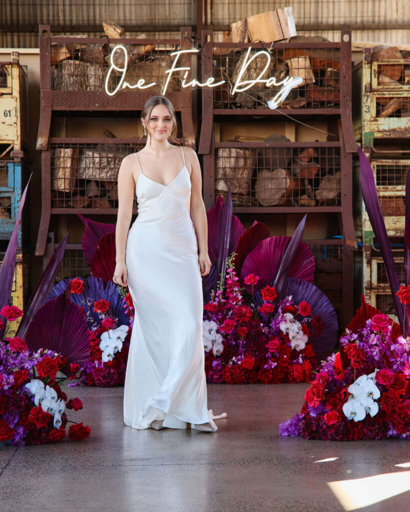Model posing in a deep V-neck strappy satin wedding dress at a bridal runway show in Melbourne