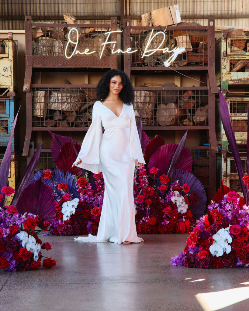 Model posing in a deep V-neck satin wedding dress with open long sleeves at a bridal runway show in Melbourne.