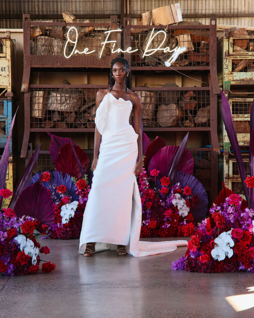 Model posing in a strapless fitted wedding dress with thigh-high slit at a bridal runway show in Melbourne.