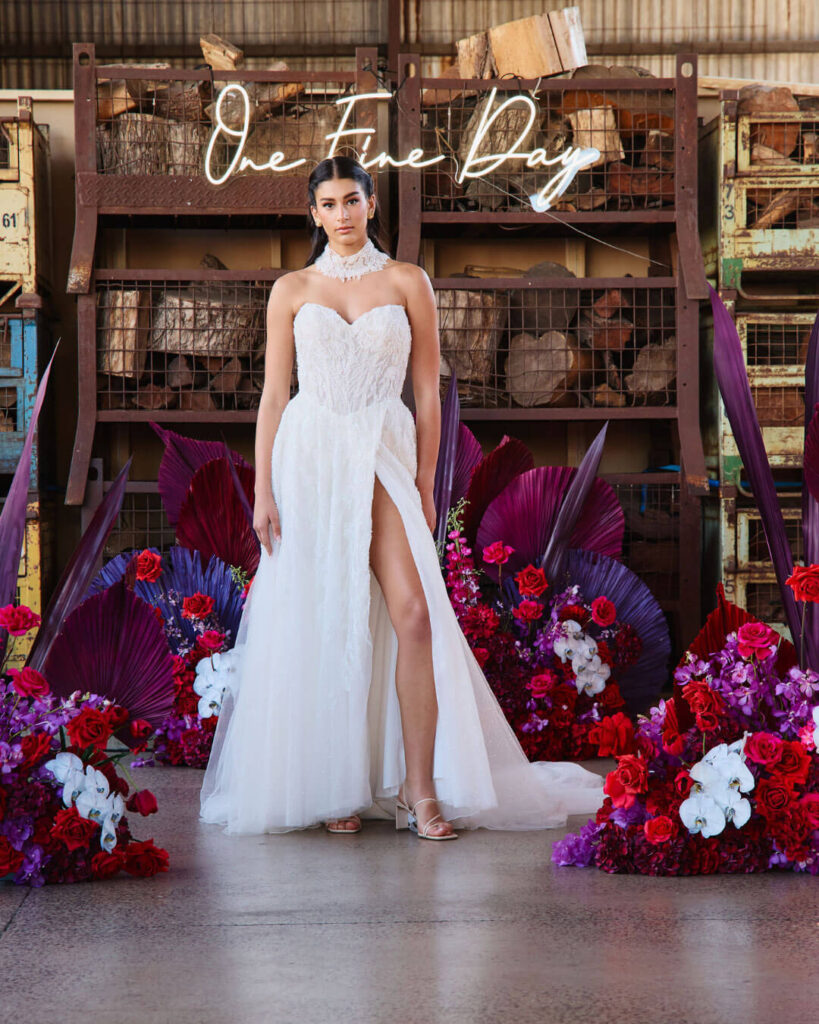 Model posing in a strapless thigh-high slit wedding dress with fabric draped around the neck at a bridal runway show in Melbourne.