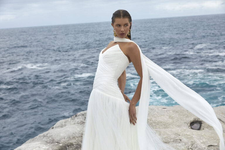 Bride in no-strap gown with sheer fabric on neck near the beach by Karen Willis Holmes Wedding Dress Australia Designer.