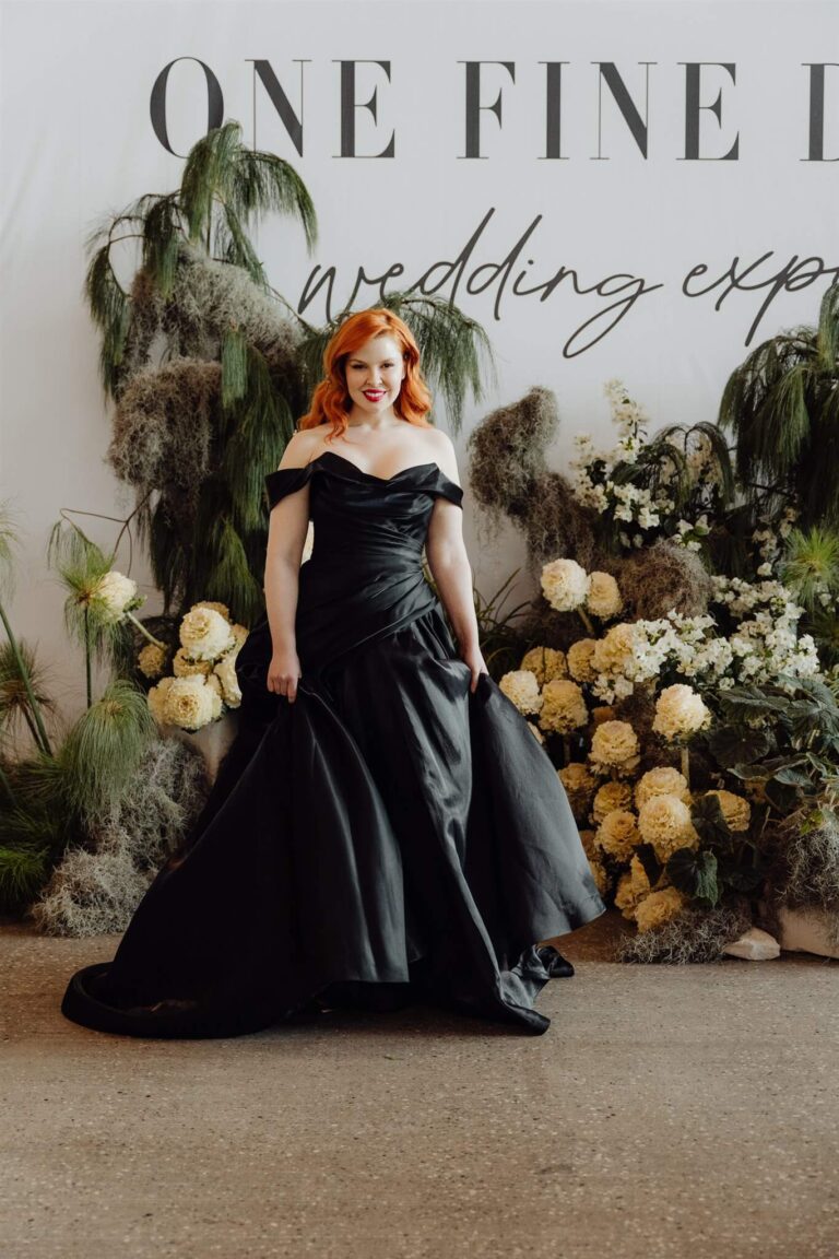 Model showcasing fitted black satin off-shoulder dress at the wedding expo in Sydney 2025