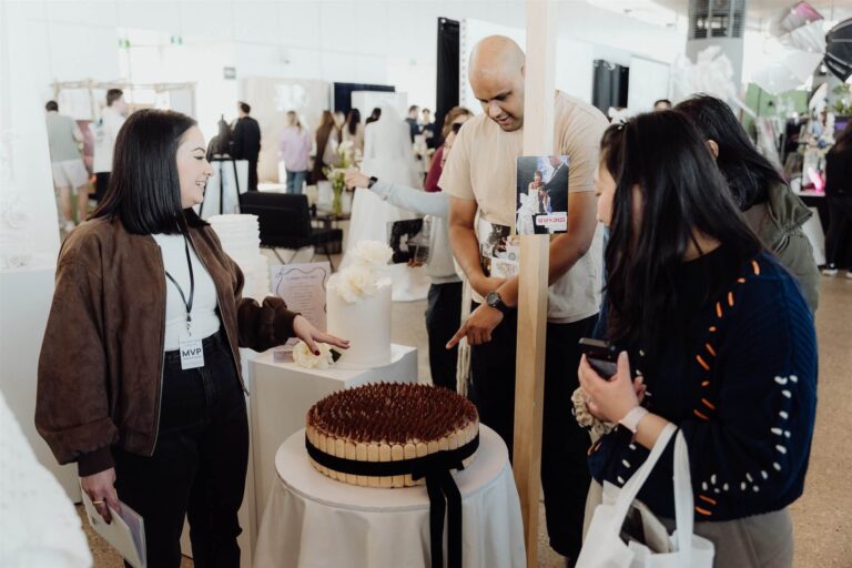 Visitors admiring wedding cake with vendor at wedding expo in Sydney 2025