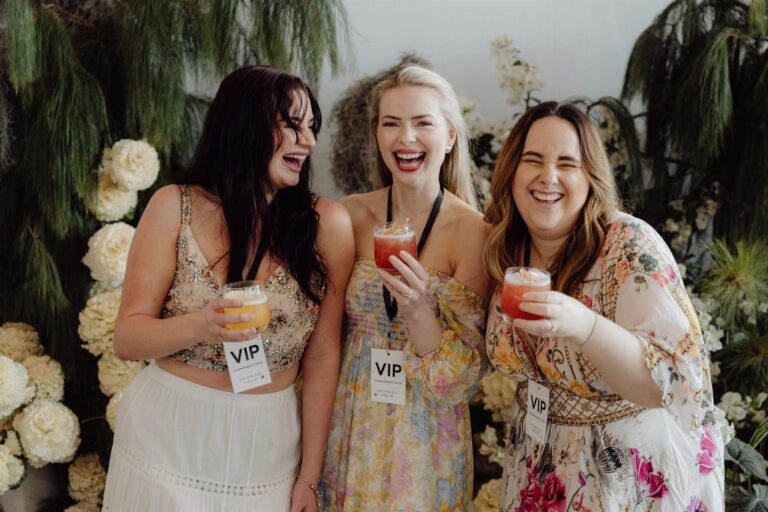 Group of three exhibitors sharing laughs with drinks at wedding expo in Sydney 2025