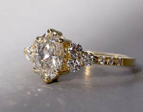 Accessories & Jewellery Listing Category James and Irisa Jewellery Close-up of oval diamond cluster engagement ring in yellow gold sparkling in the sunshine from James and Irisa Jewellery Diamond Engagement Rings.