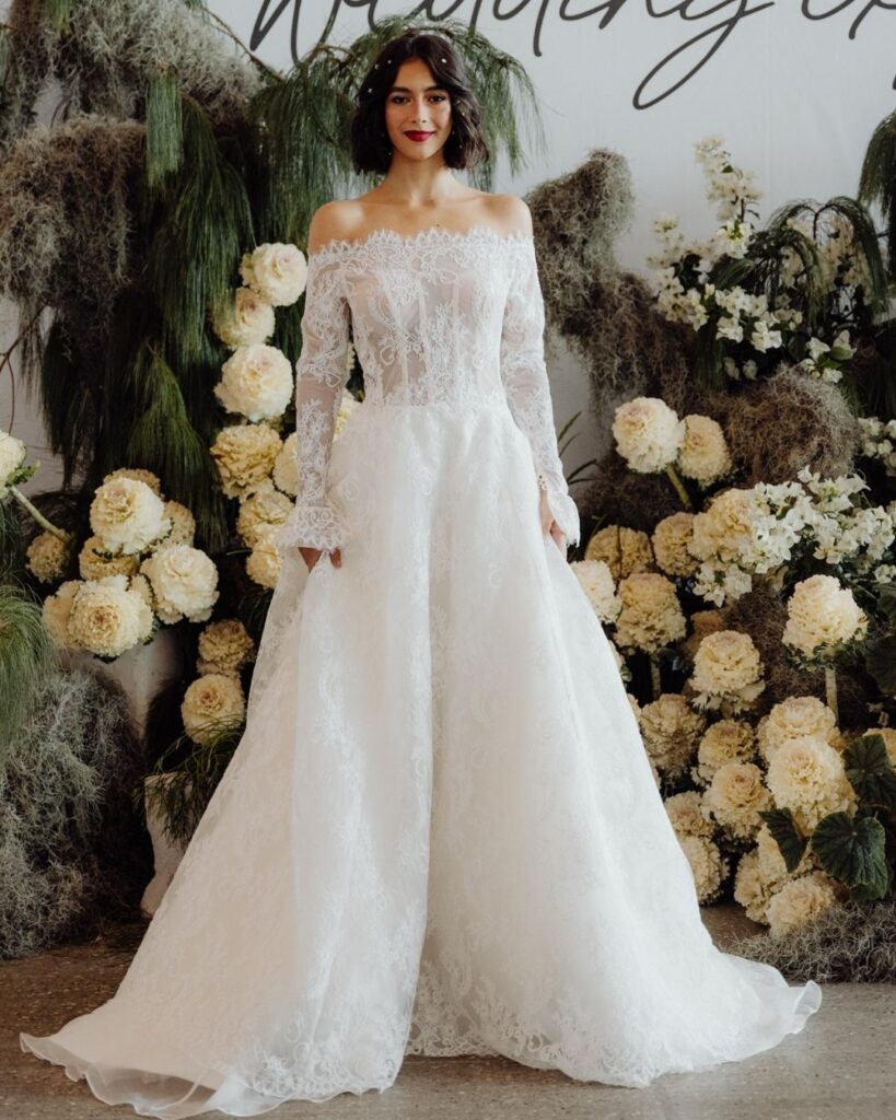 Model showcasing off-shoulder lace gown with long sleeves at bridal runway show in Sydney 2025