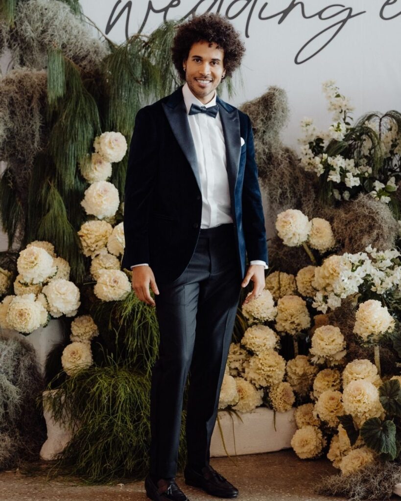Model showcasing fitted navy blue velvet suit with satin black pants at bridal runway show in Sydney 2025