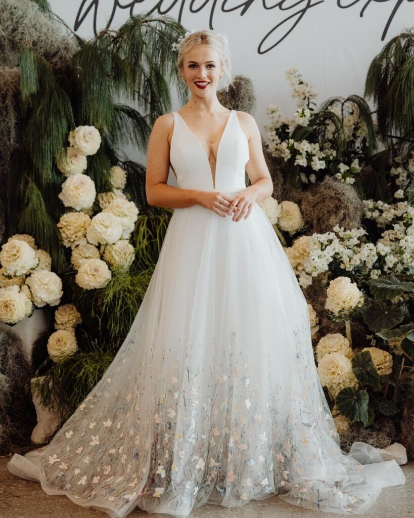 Close-up of butterfly detail below skirt on deep V cut sleeveless dress during bridal runway show in Sydney 2025