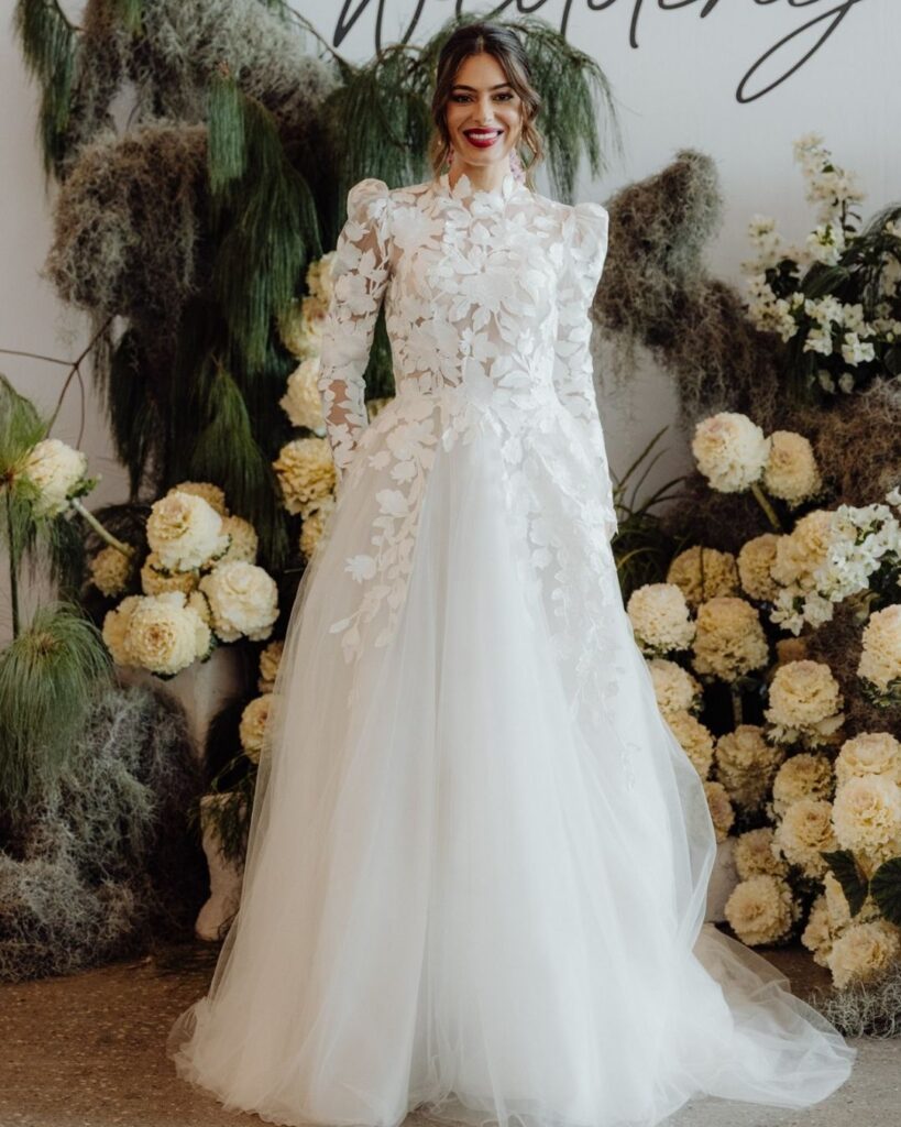 Model showcasing fitted chiffon gown with long sleeves, high neckline, and leaf pattern at bridal runway show in Sydney 2025