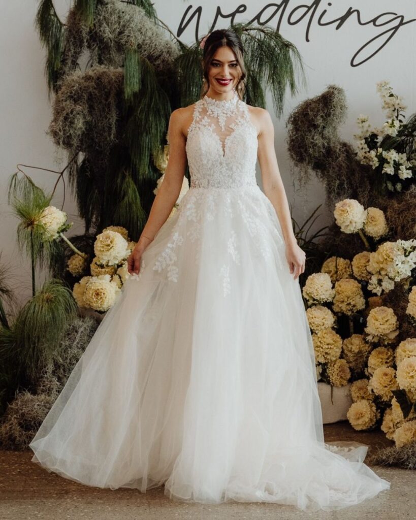 Close-up of high neckline sleeveless lace top and flowing chiffon skirt gown during bridal runway show in Sydney 2025