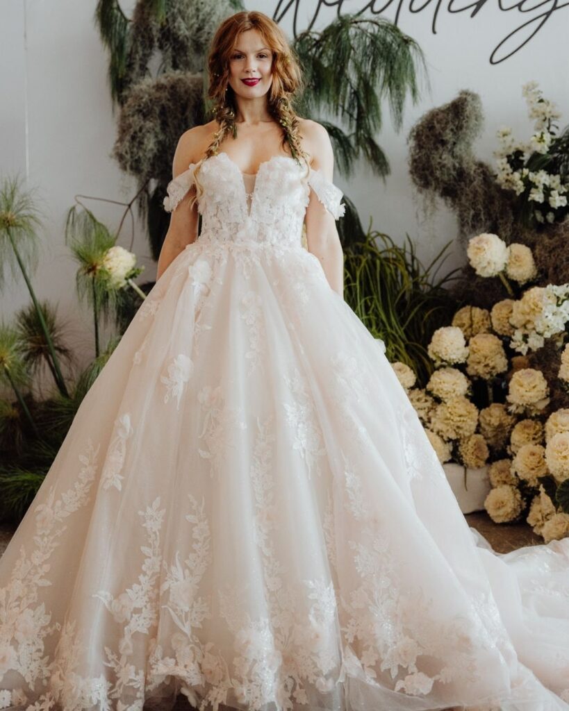 Bridal runway show in Sydney 2025 featuring a model in elegant off-shoulder chiffon ball gown with white floral accents
