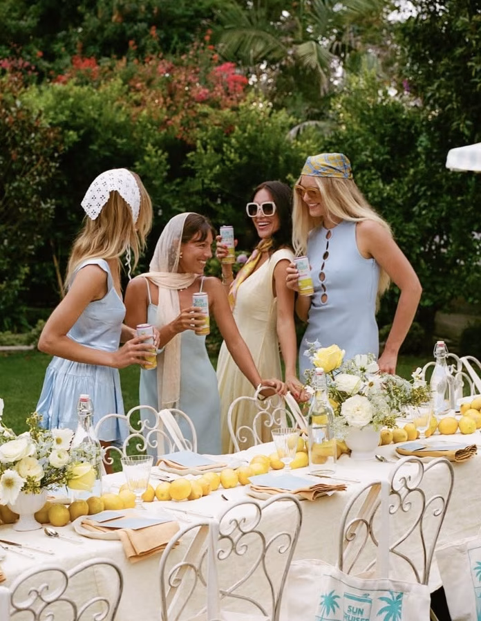 Four women talking and laughing together in front of a lemon themed lunch table
