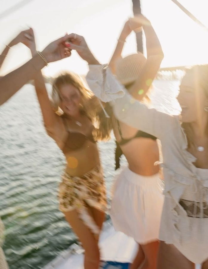 Women dancing on a yacht at sunset at a hens party in Australia
