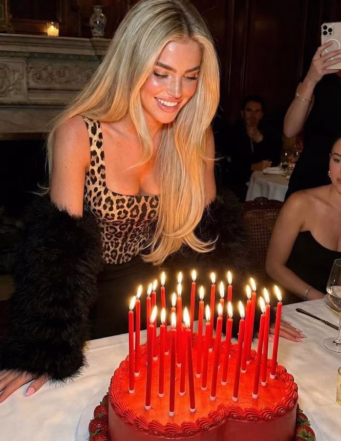 A bride in a leopard print top blowing out the candles on a red heart cake
