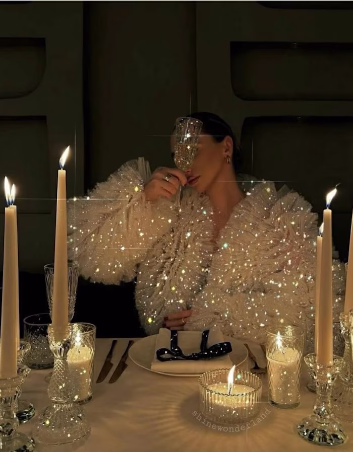 A woman in a sparkly jacket holding a champagne glass up to the camera
