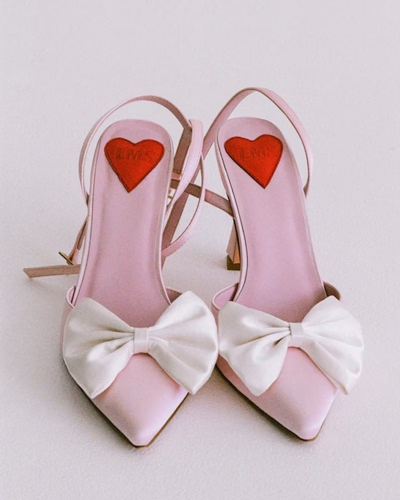 A pair of pink bridal heels with white bows